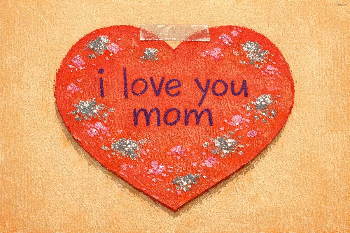 Close-up of the wall. A handmade paper heart fills most of the frame — construction paper, glitter glue, wobbly crayon l